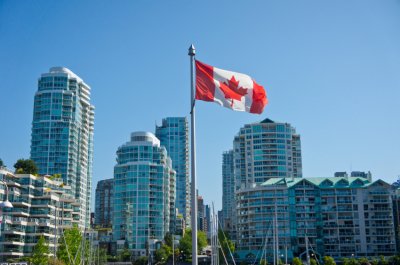 A Canadian flag flutters over in an urban setting on a summer day
