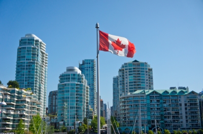 The Canadian flag fluttering in front of office buildings