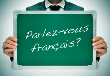 A person holding a board with French written across it