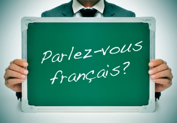 A person holding a board with French written across it