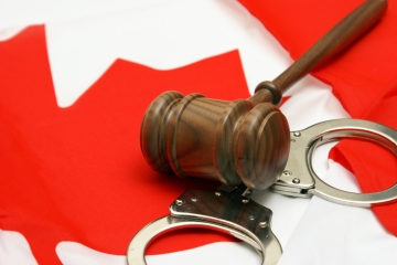 A gavel and set of handcuffs resting on a Canadian flag